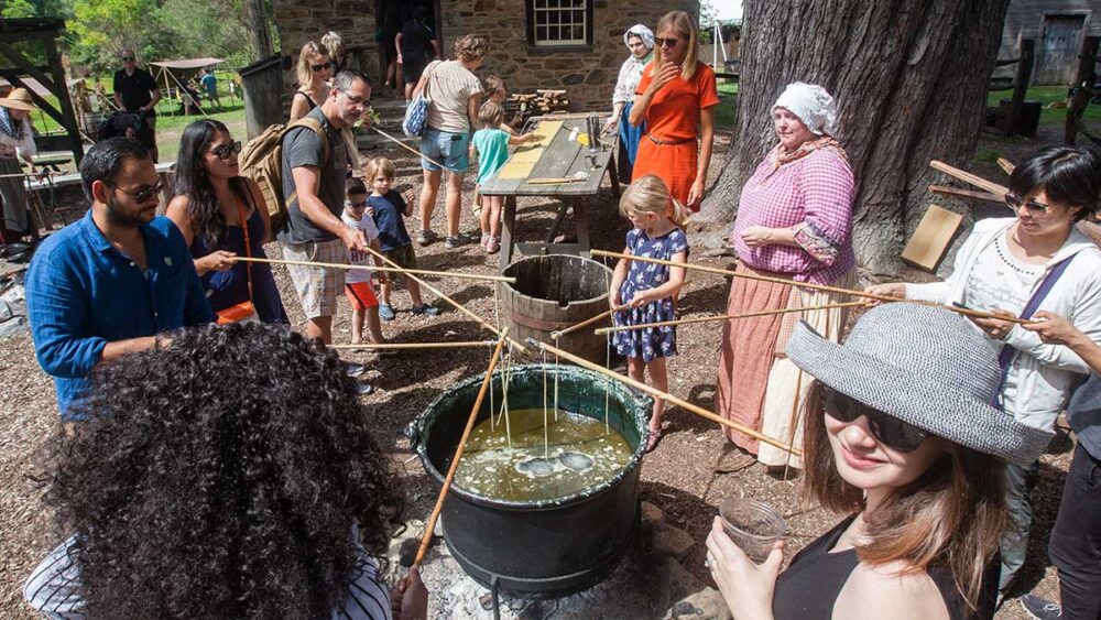 Candle Dipping A crowd dips string into a large pot to make candles