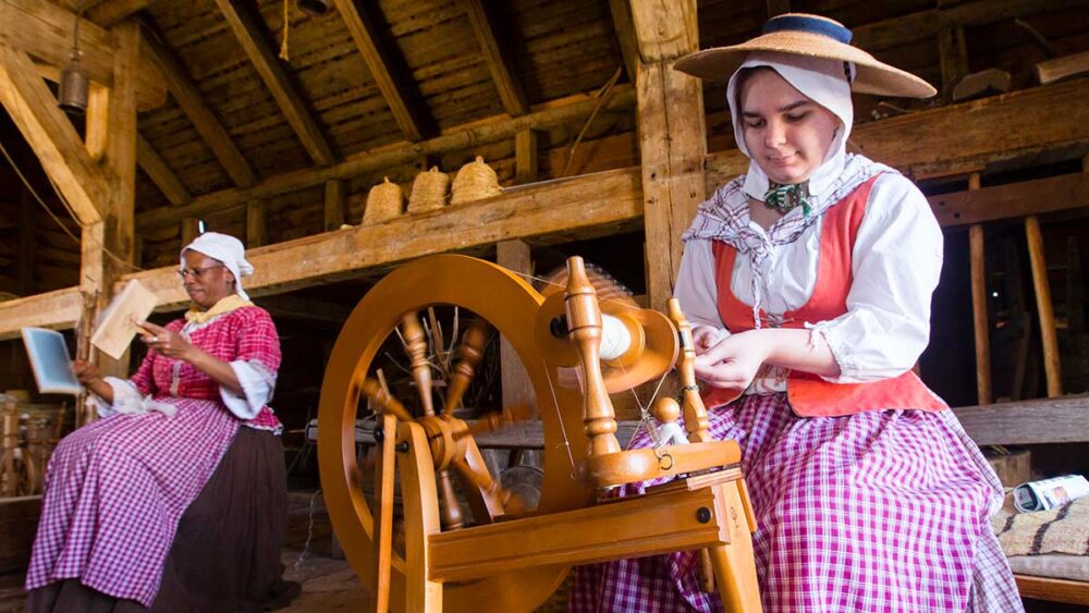 Spinning Wool Woman in historical costume spinning wool with woman behind her carding wool